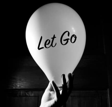 Black and white photo of hand holding a balloon that says "Let Go"