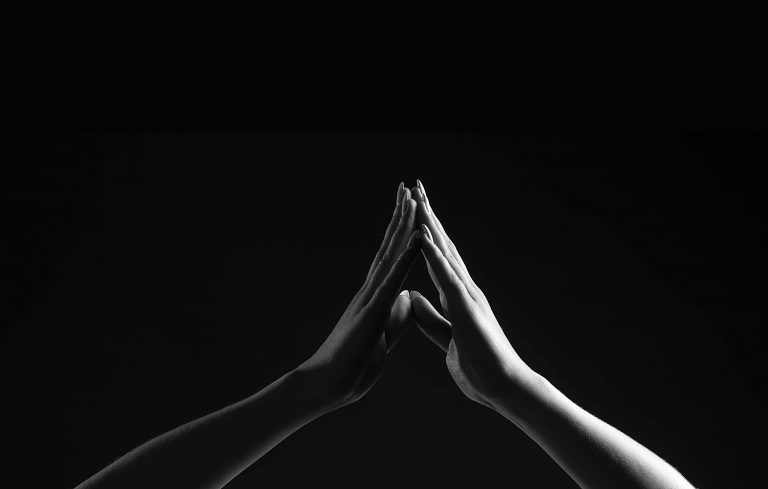 Black and white photo of two hands coming to touch at the middle