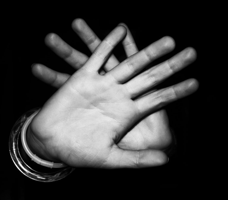 Black and white picture of palms of hands crossed and pushing away from camera