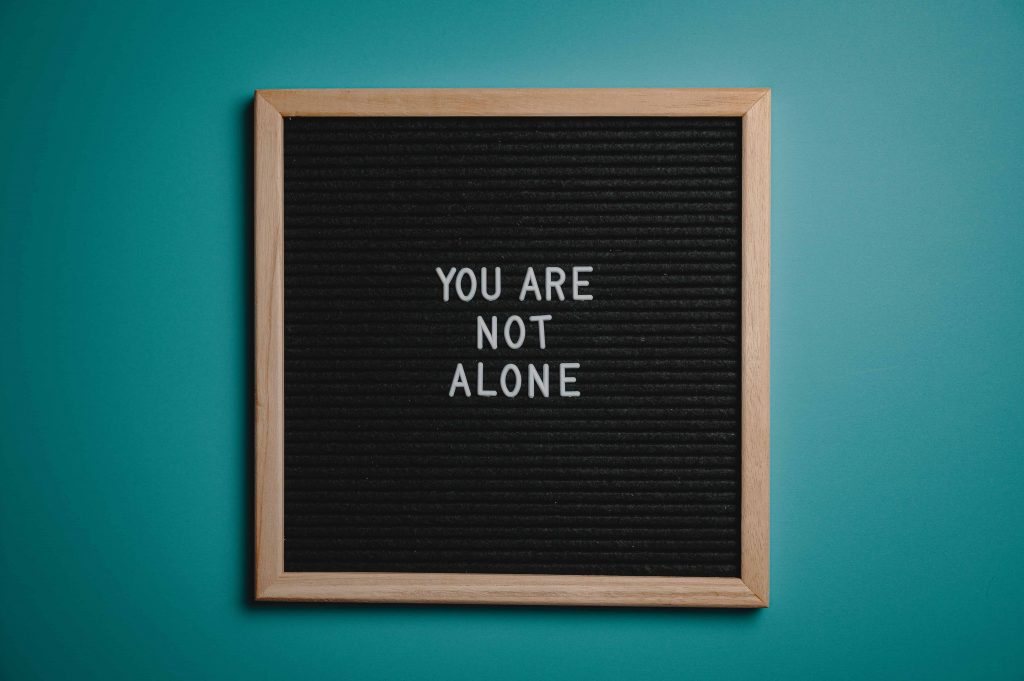 You are not alone quote on a letterboard on blue wall