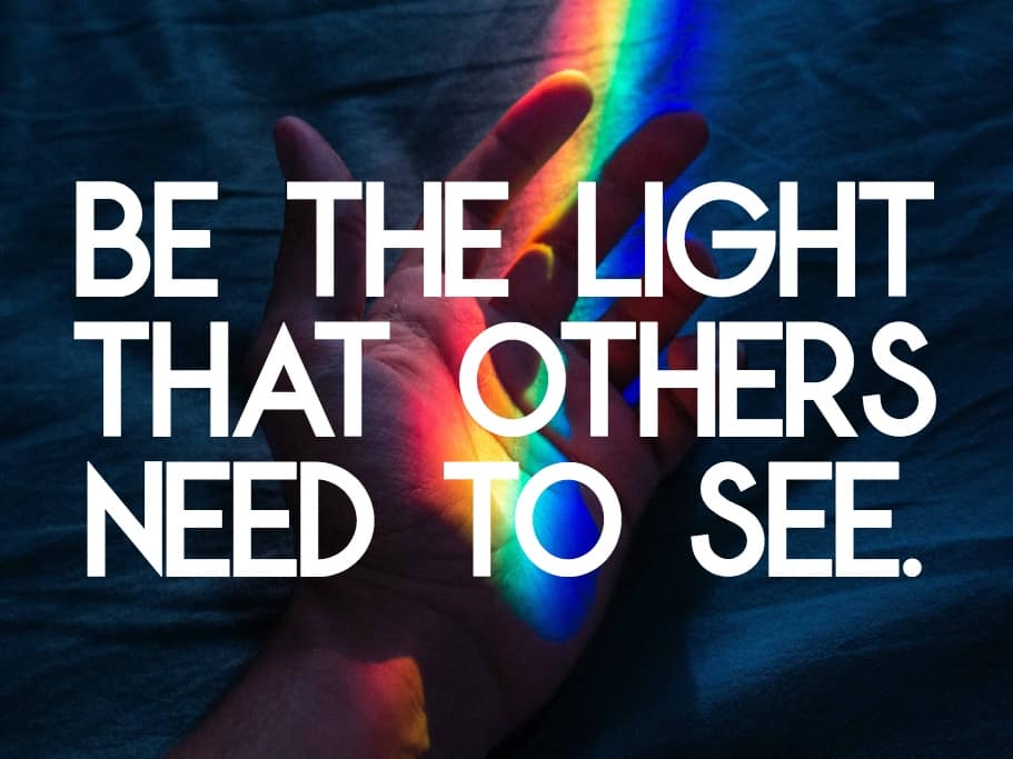 "Be the Light that Others Need to See" quote over a hand with rainbow light going across