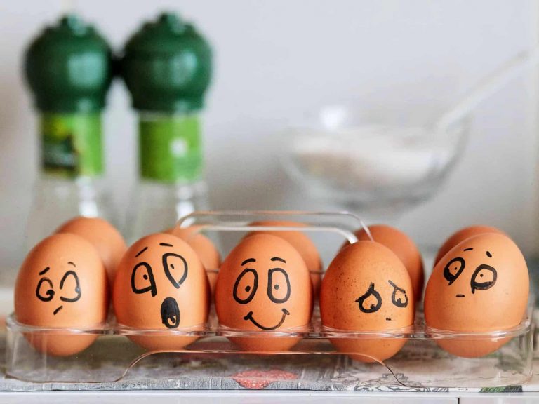 A carton of eggs with a variety of emotions drawn on