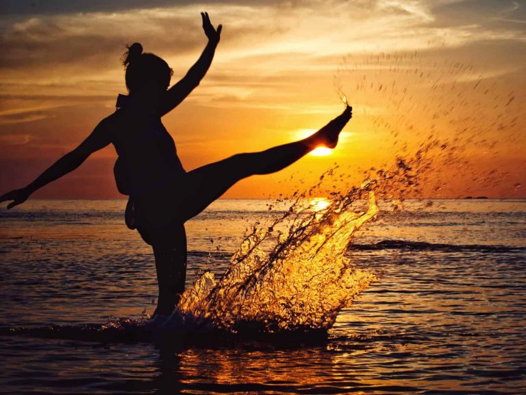 Person expressing positive emotion, splashing water during sunset