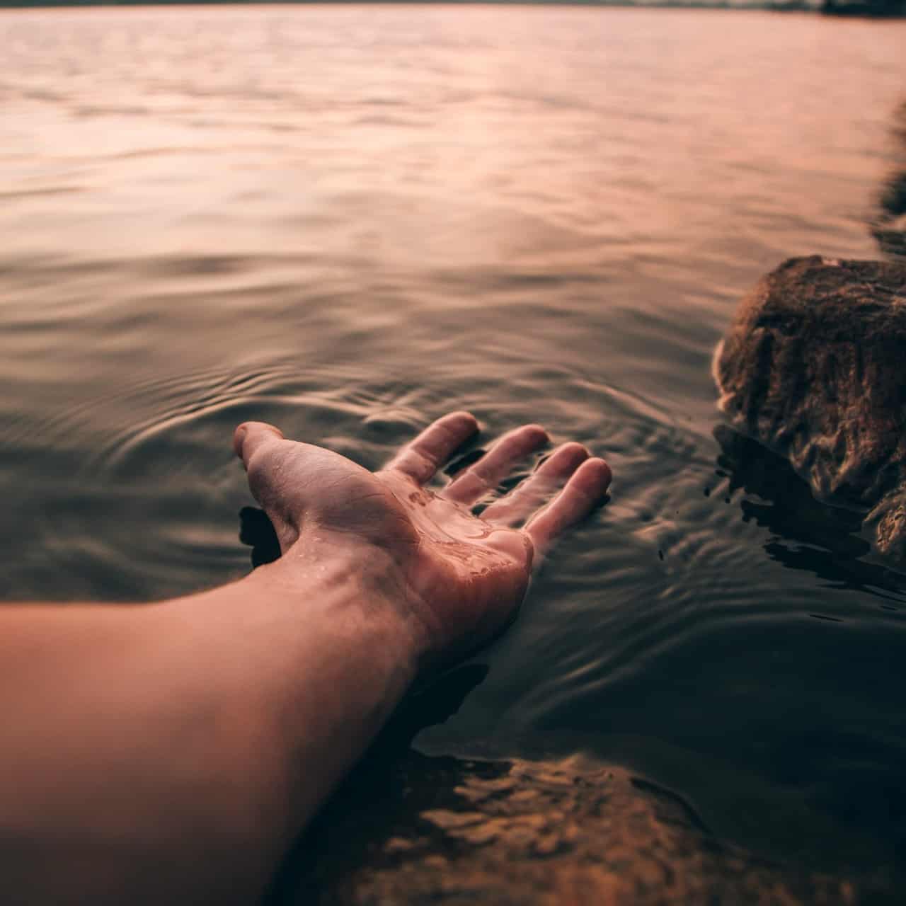 Person putting their open hand into the water