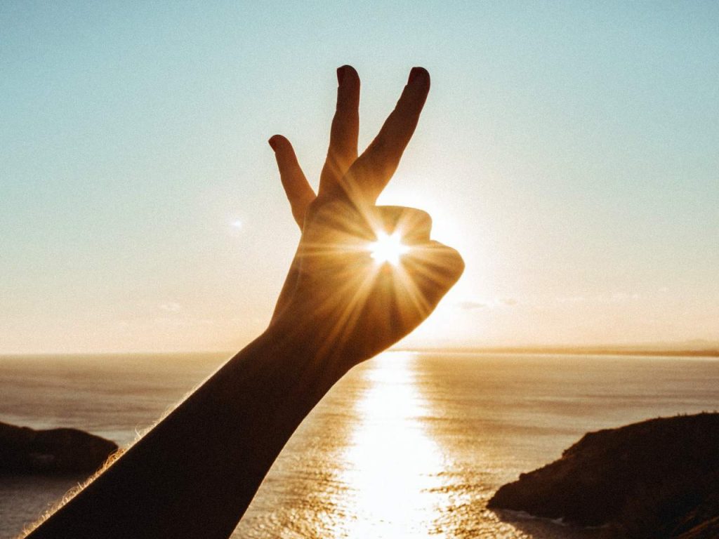 Person holding their hand to the sunlight in an "okay" gesture