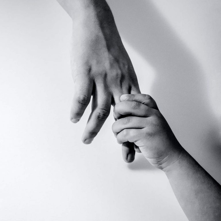 A young person's hand holding an adult's hand