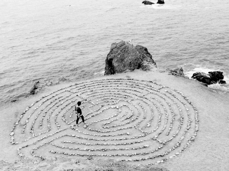 Person walking through a stone maze on the beach