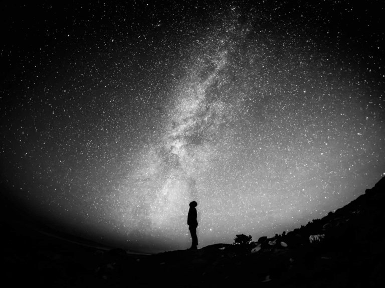 Person standing outside and looking up at the stars