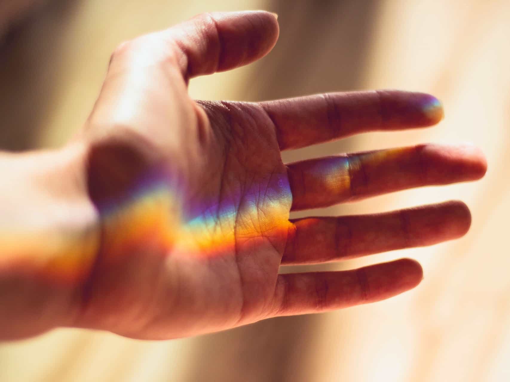 A streak of rainbow light going across a person's open hand
