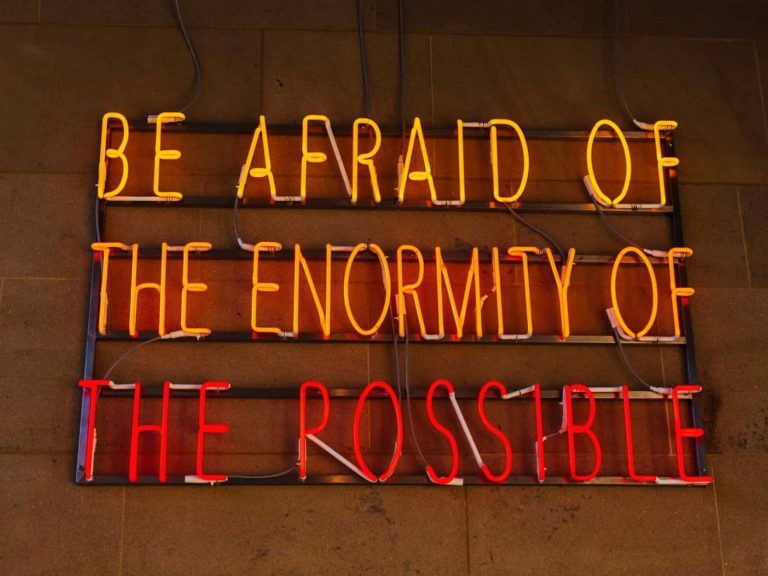 "Be afraid of the enormity of the possible" quote on a neon sign