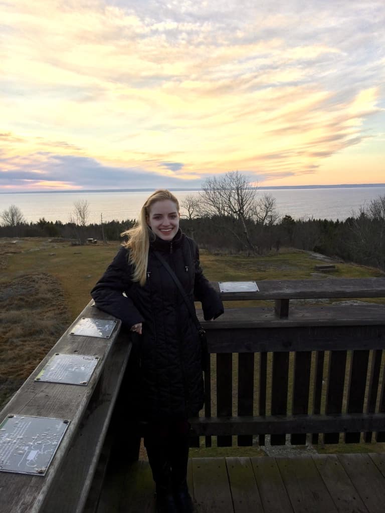 Kee standing in the corner of a lookout over land and water