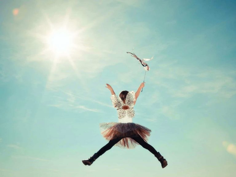 child jumping in costume against sky