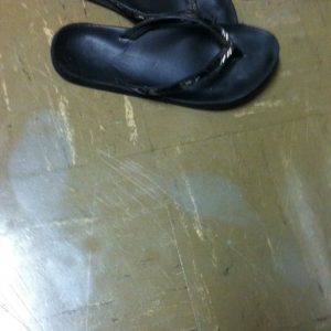 Grey ghost shoe prints on a tile floor next to flip flops