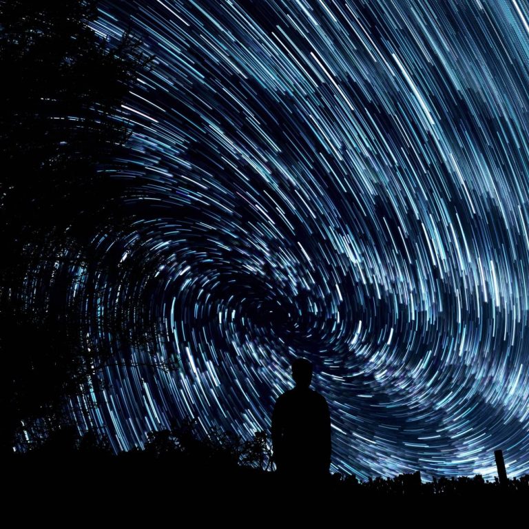 A silhouette against a star trail spiral