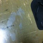 Grey ghost shoe prints on a tile floor next to flip flop