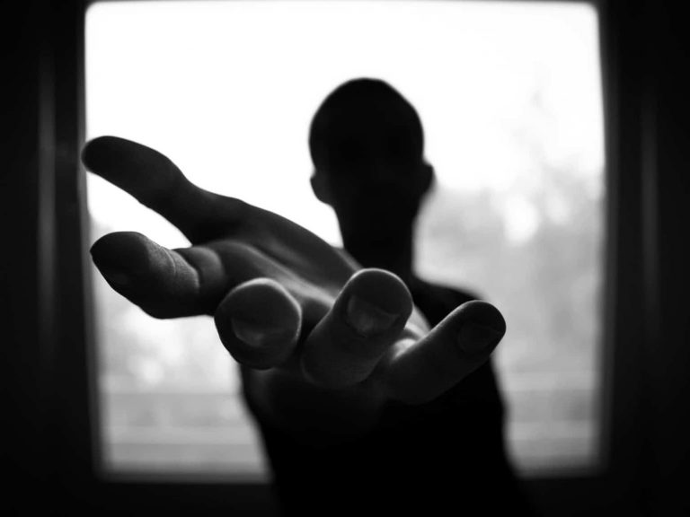 Black and white picture of a person holding out their hand towards the camera