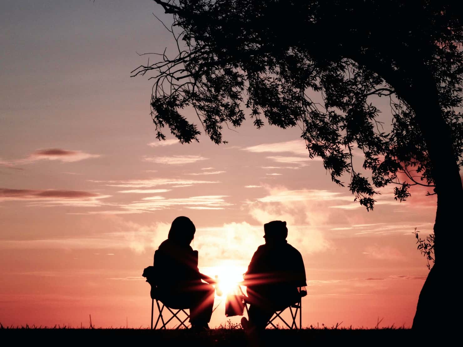two people sitting talking outside at sunset