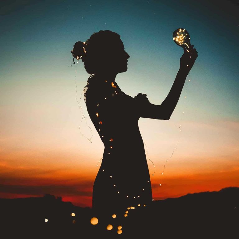 A person holding a lightbulb that's cord wraps around them