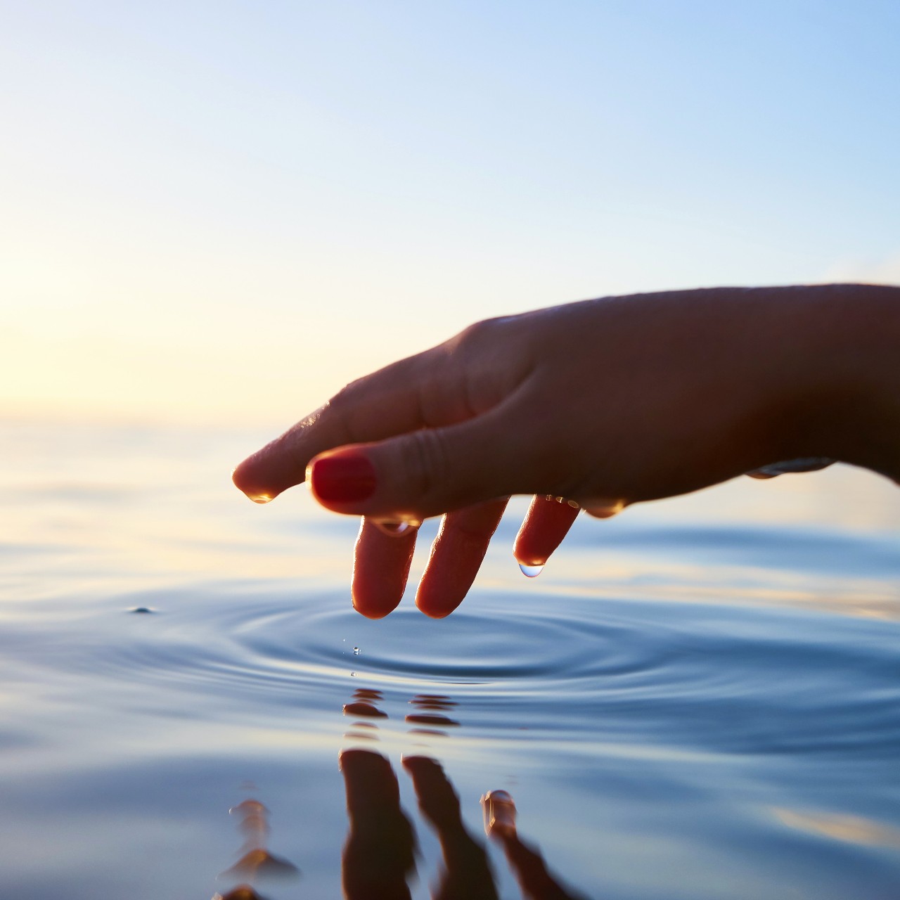 A hand touching the surface of the water