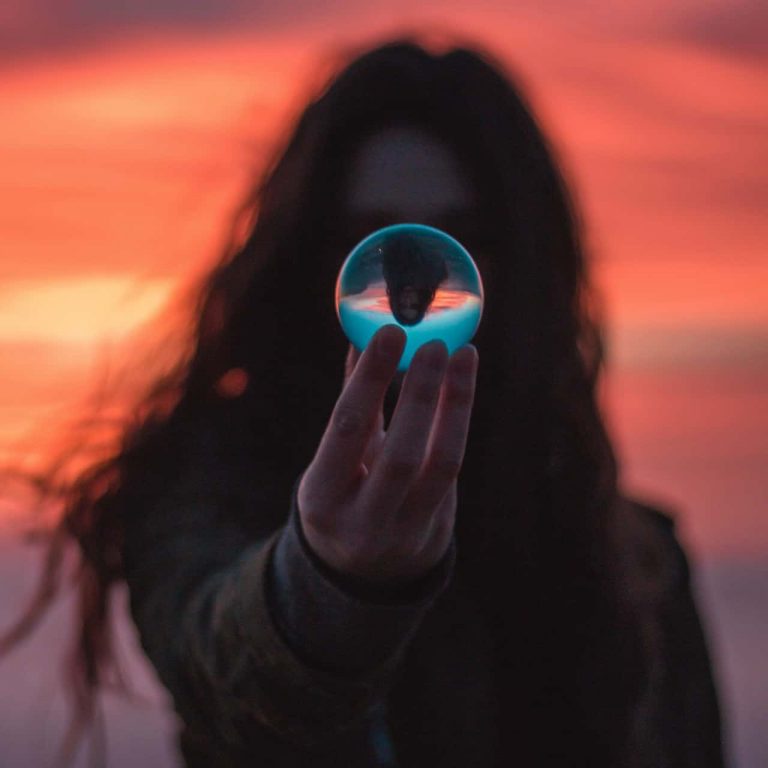 A person holding a glass ball with their upside down reflection