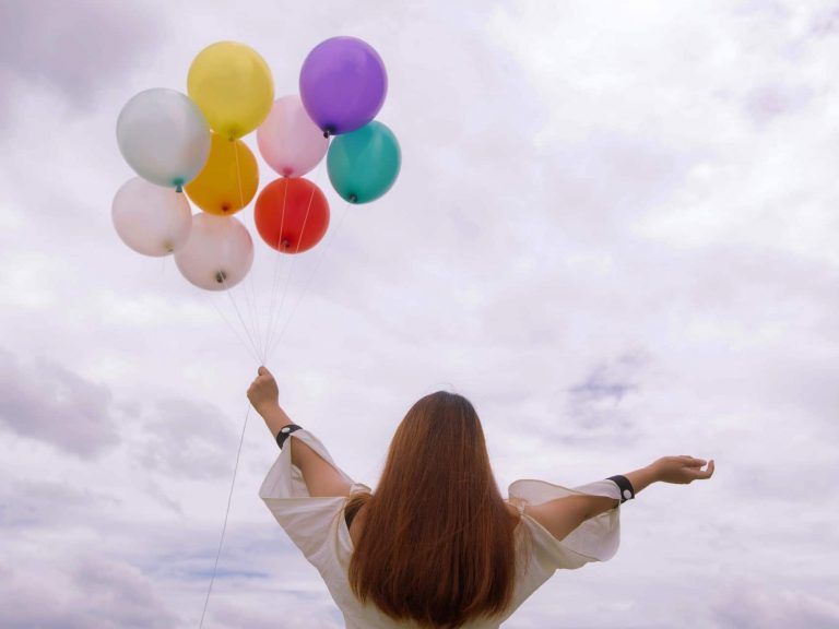 A person happily holding balloons in the air