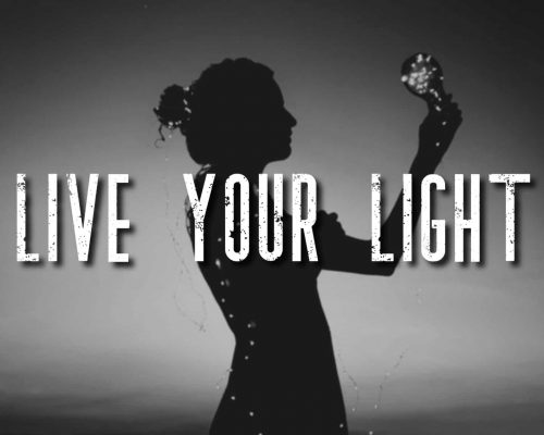 "Live your light" mantra over picture of a person wrapped in lights and holding a light bulb to the sky