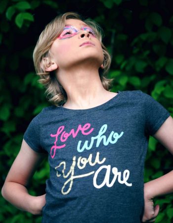 A child wearing a shirt that says, "Love who you are"